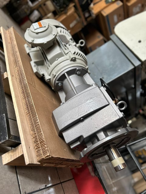 Industrial electric motor mounted on wooden board in workshop setting