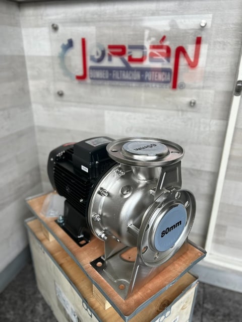Industrial centrifugal pump with black motor mounted on wooden base displayed in display case with JURDEN company logo