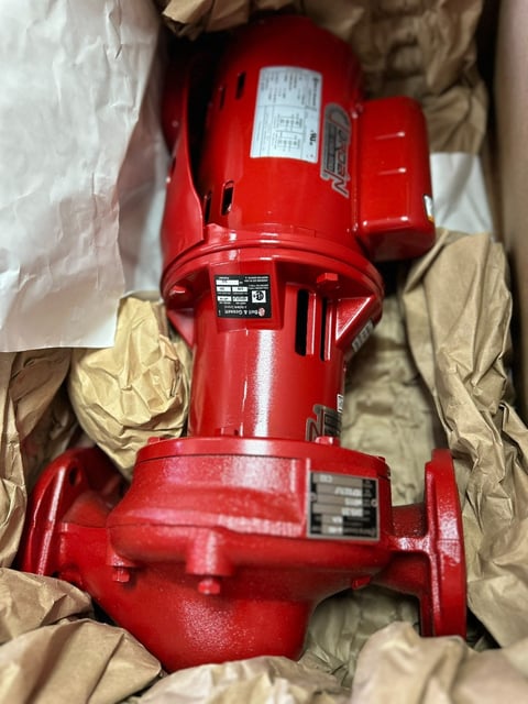 Red industrial electric motor or pump packaged in brown paper wrapping