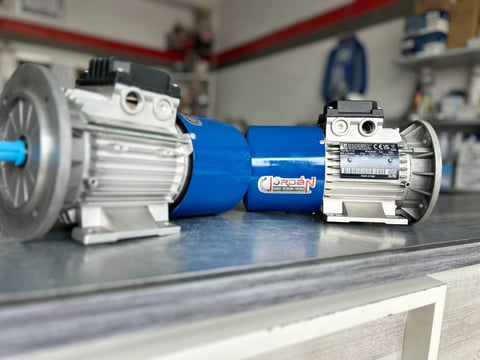 Three electric motors displayed on a workbench, featuring silver and blue industrial motor units with visible components